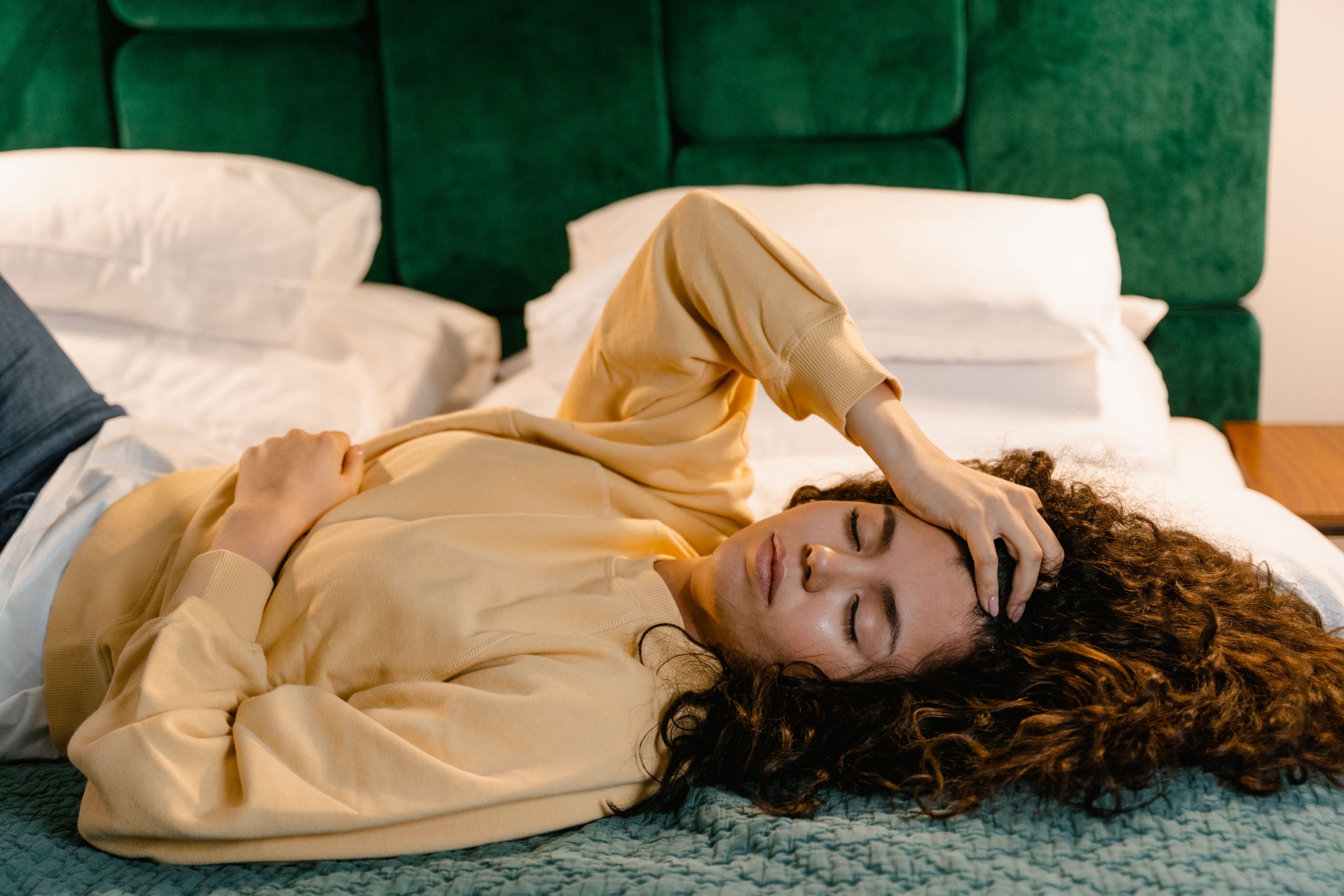 Femme au lit, main au front, détente sereine