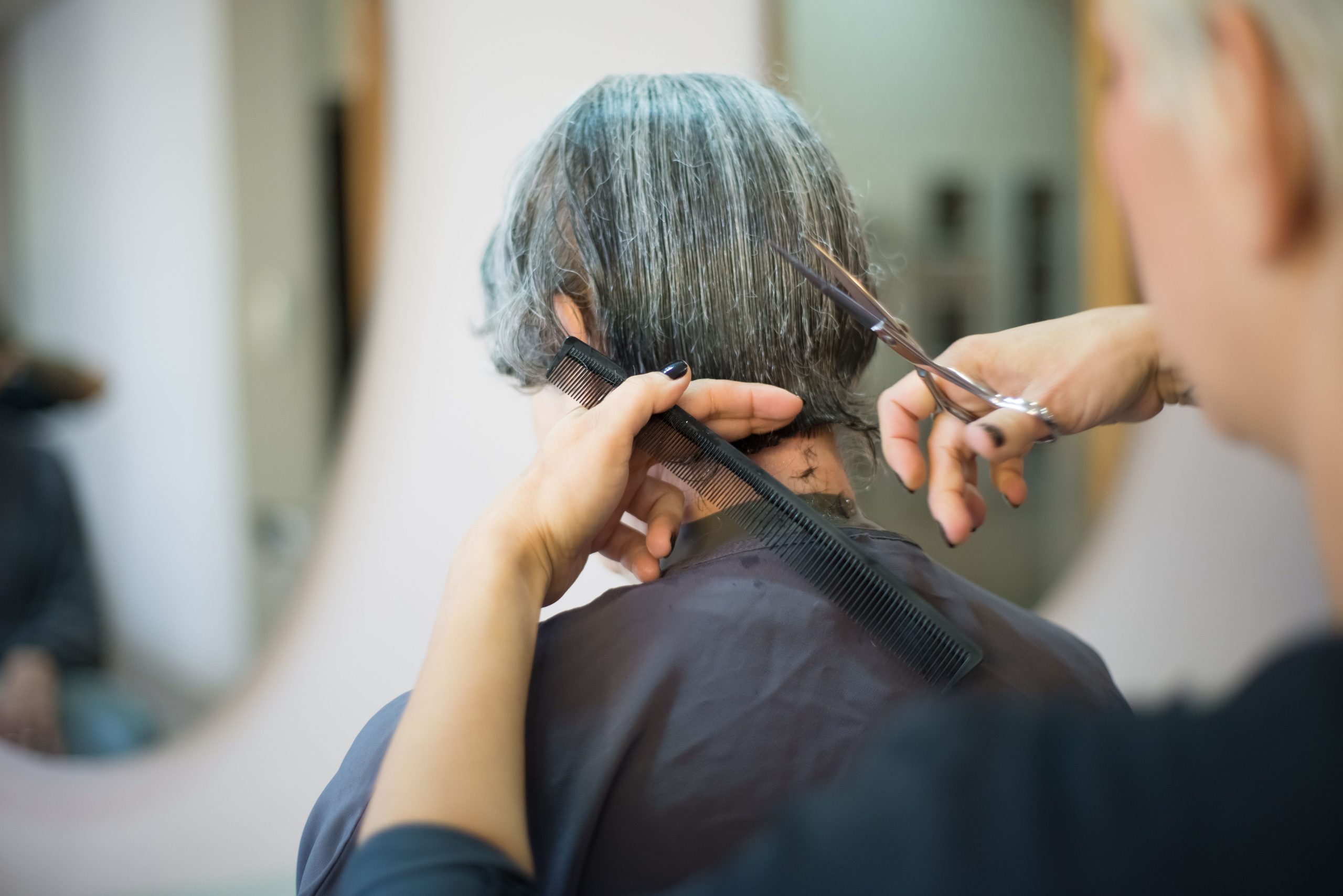 Coiffeuse coupant les cheveux d'une cliente en salon