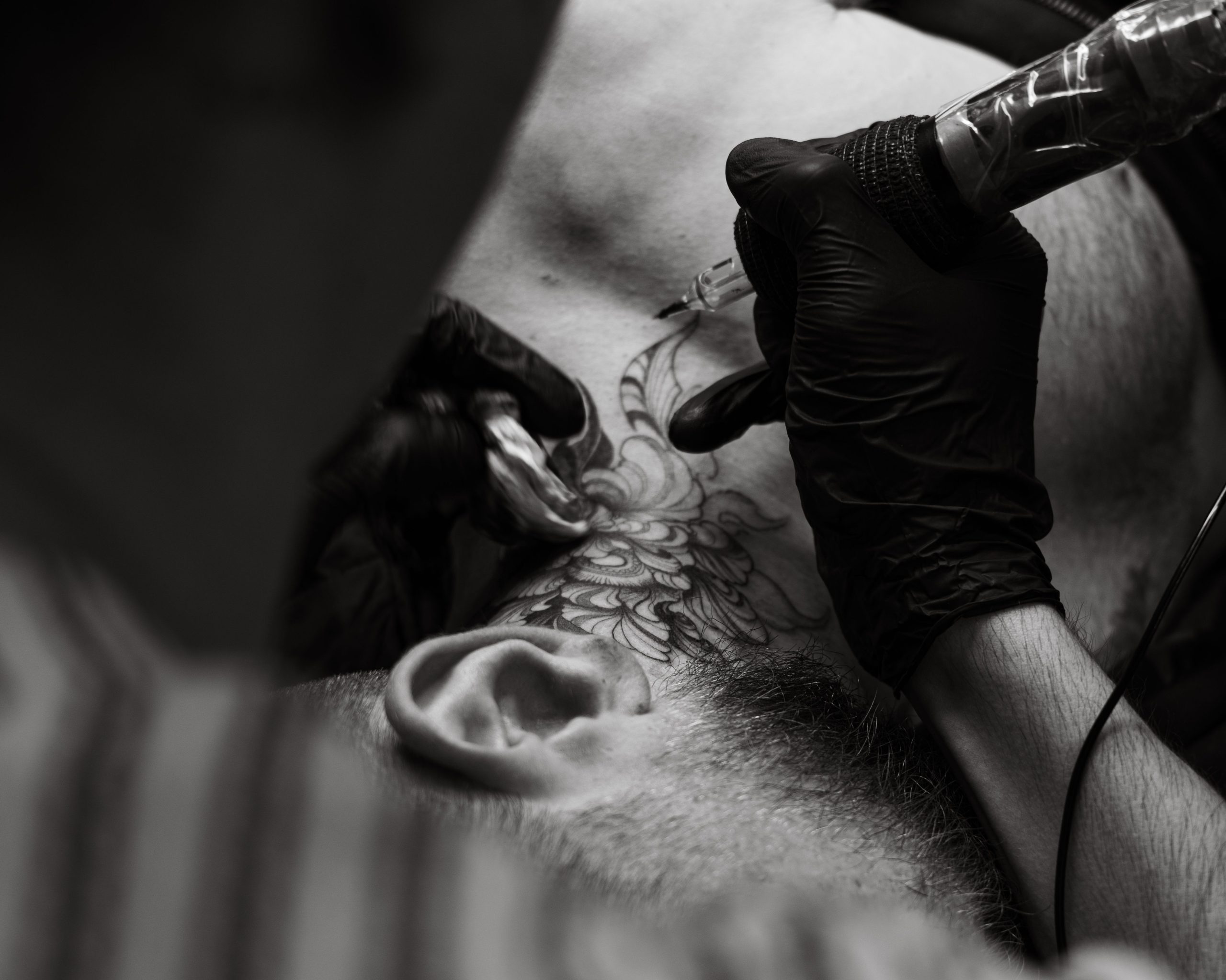 Tatoueur réalisant un motif floral sur le cou