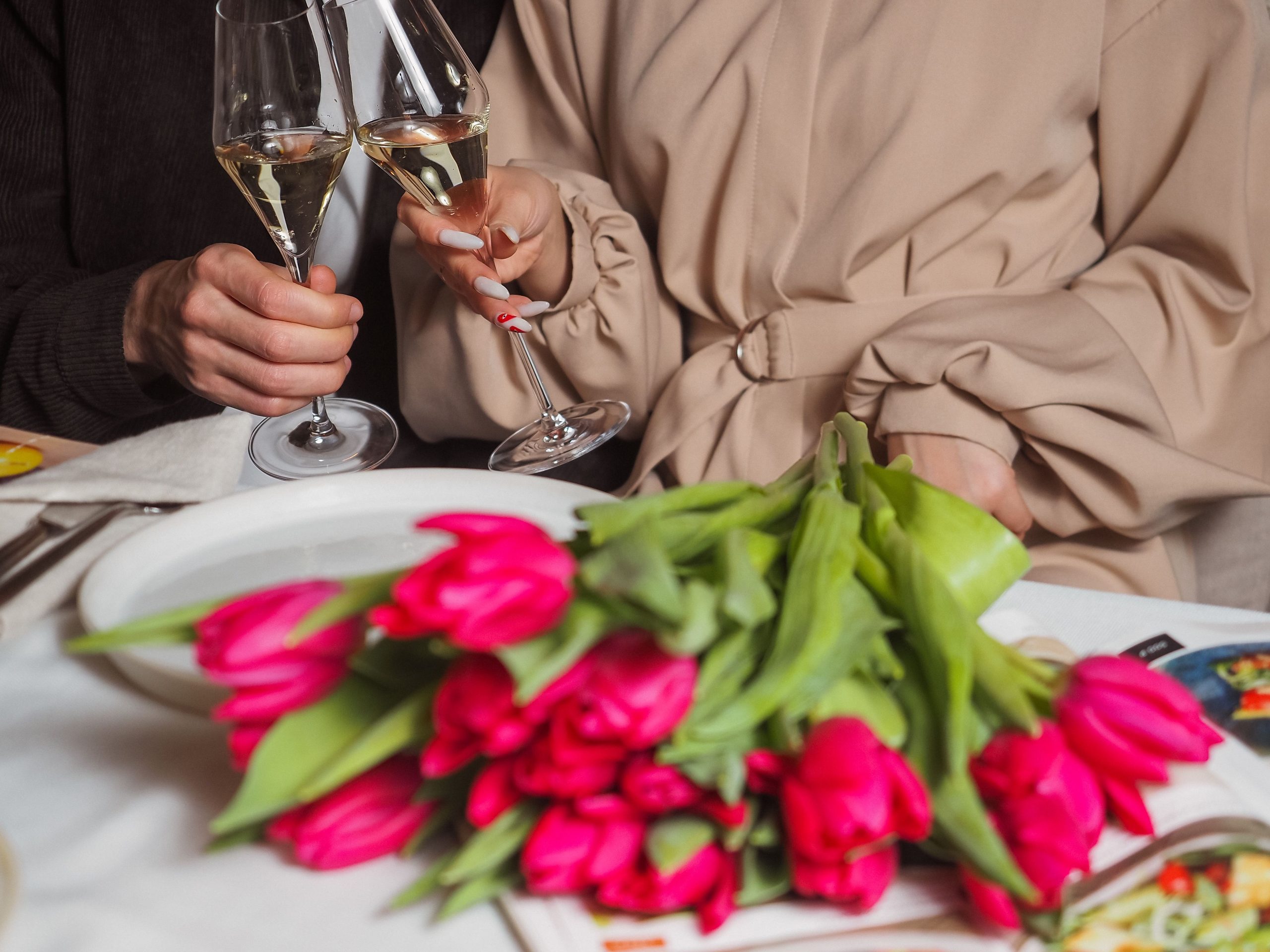 Couple trinquant au champagne près de tulipes roses