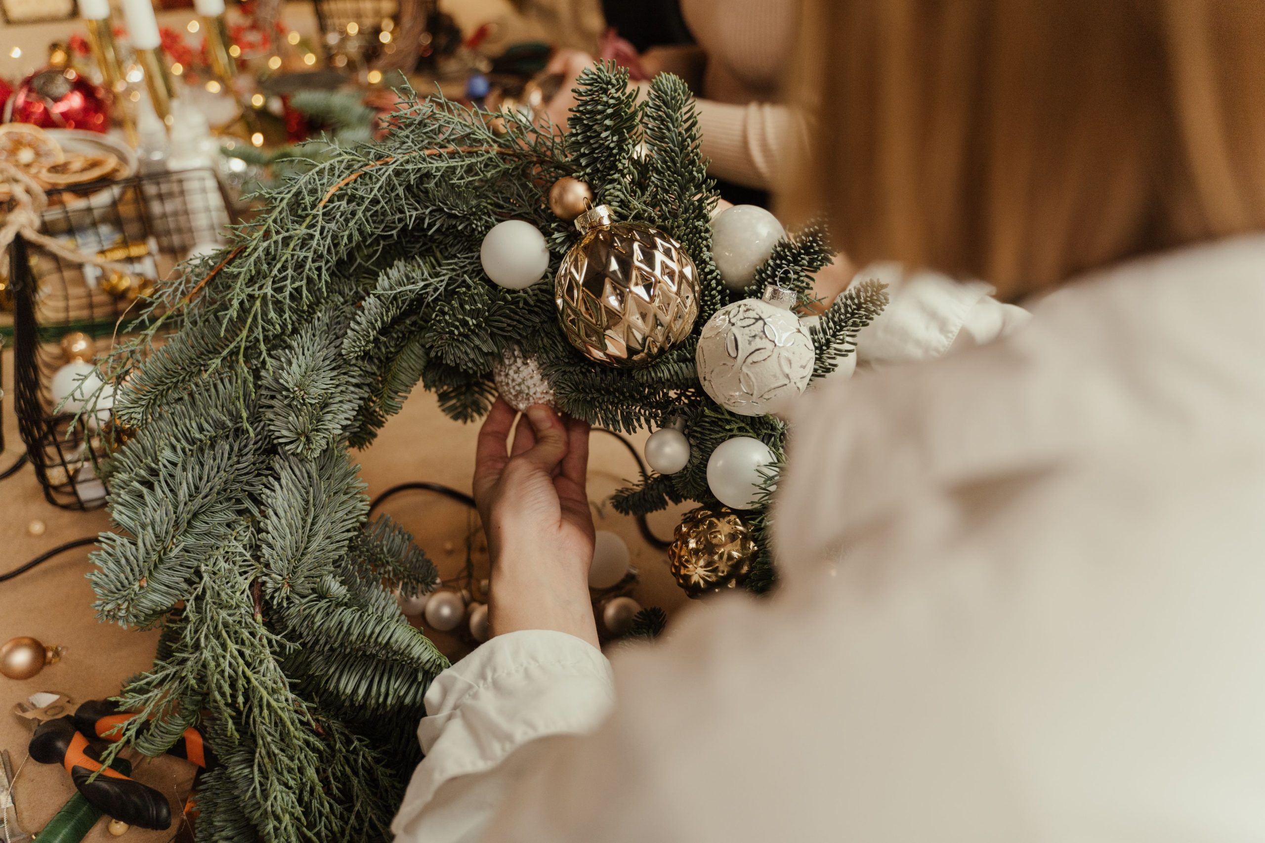 Mains créent couronne festive avec ornements et branches