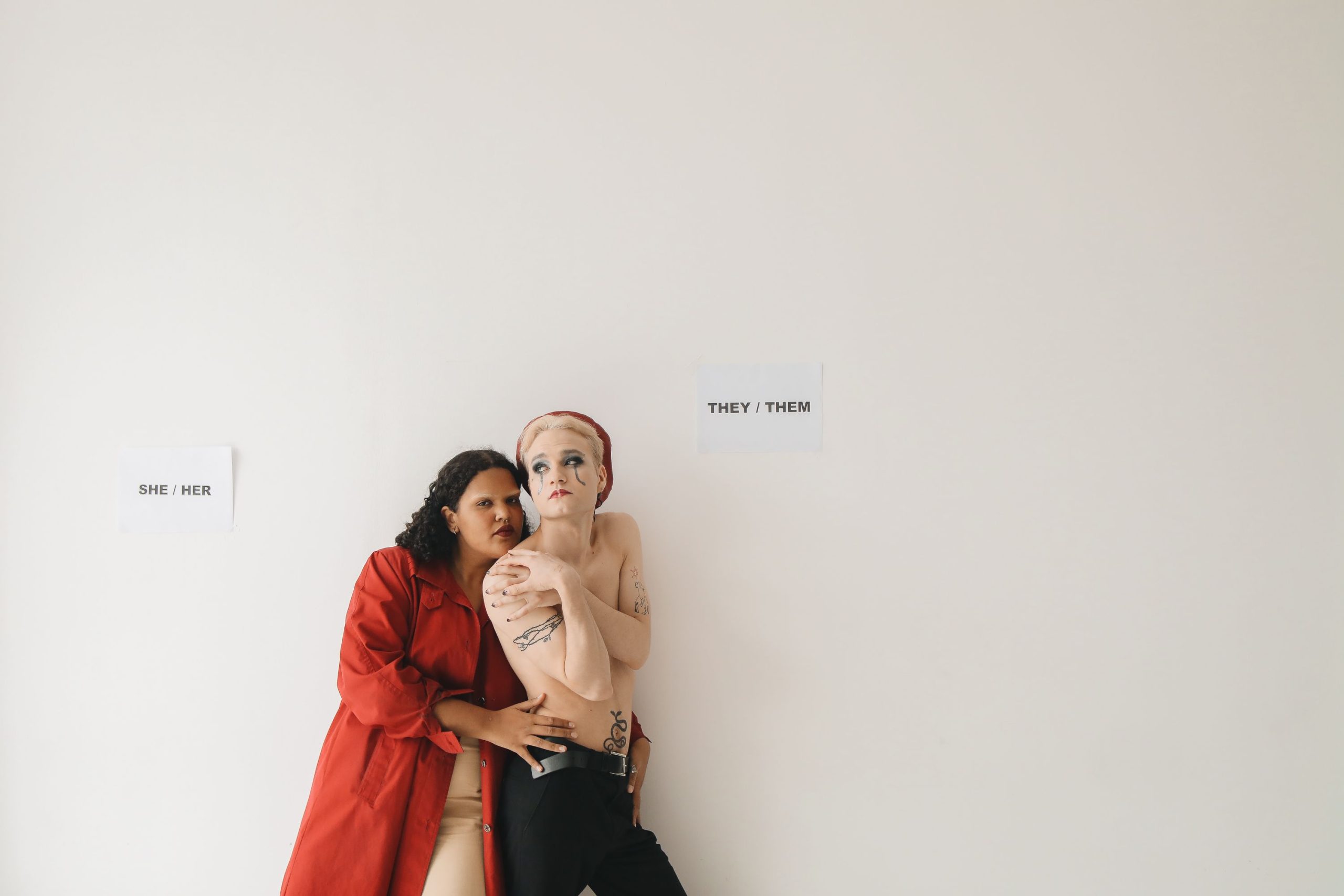 Portrait studio de deux personnes affichant leurs pronoms